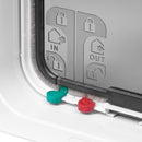 Eine Nahaufnahme der linken Ecke der weißen Katzenklappe zeigt zwei der manuellen Schlösser, die rot und grün sind, sowie die wetterfeste Bürste