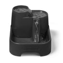 Eine Vorderansicht des leeren dreistufigen Haustier-Trinkbrunnens in grau, geeignet für kleine Hunde und alle Katzenrassen, vor einem weißen Hintergrund.