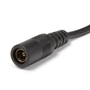 Eine Nahaufnahme eines schwarzen Stromkabel-Steckerendes, die einen zylindrischen Buchsenstecker mit sichtbaren Metallkontakten in der kreisförmigen Öffnung zeigt, der an ein schwarzes Kabel mit Zugentlastungsrippen in der Nähe des Steckergehäuses angeschlossen ist