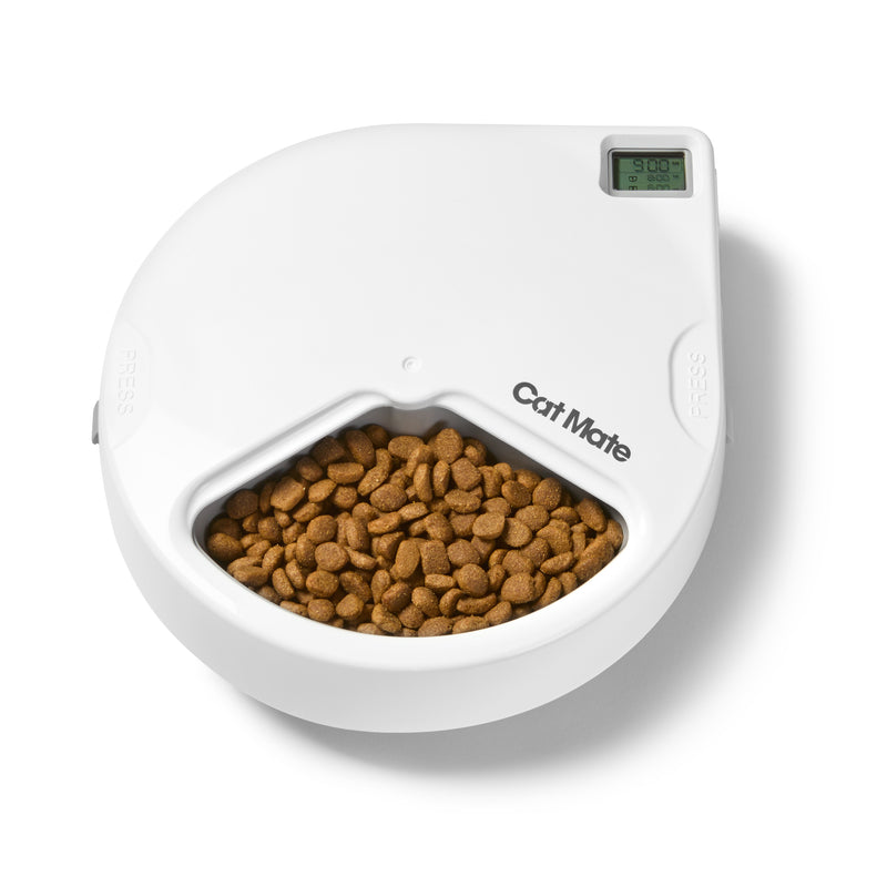 Ein weißer, runder automatischer Haustierfütterer mit dem Markennamen 'Cat Mate', der auf der Vorderseite sichtbar ist. Der Fütterer hat ein geschwungenes, modernes Design mit einem schalenförmigen Fach, das mit braunen Trockenfutter-Kroketten für Katzen gefüllt ist. In der oberen rechten Ecke befindet sich ein kleines digitales Display, das '2:00' anzeigt. Das Gerät scheint ein zeitgesteuertes Fütterungssystem für Katzen oder kleine Hunde zu sein, fotografiert vor einem weißen Hintergrund.