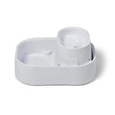 Eine schräge Frontansicht des weißen Dog Mate Haustierbrunnen mit Wasser, das langsam von der oberen Ebene in die teilweise gefüllte untere Ebene tropft, vor einem weißem Hintergrund