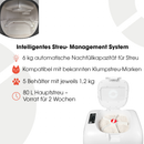 Infografik, die das intelligente Streumanagement-System einer automatischen Katzentoilette zeigt. Das Hauptbild zeigt die offene Draufsicht der weißen Einheit mit frischer klumpender Streu und einem sichtbaren roten Reinigungsrechen-Mechanismus. Das kreisförmige Einsetzbild zeigt den inneren Streuausgabemechanismus. Der Text beschreibt Funktionen: 6 kg automatische Streu-Nachfüllkapazität (Glühbirnen-Symbol), funktioniert mit bevorzugten klumpenden Streumarken (Katzengesicht-Symbol), 5 Reservoirs × 1,2 kg j